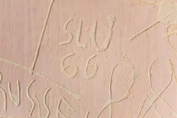 Detailansicht von Texten die in eine Wand gekratzt wurden.