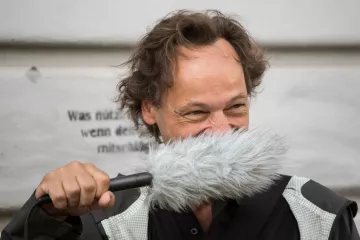 Bertram Weisshaar trägt das Aufnahmegerät als Schnurbart.