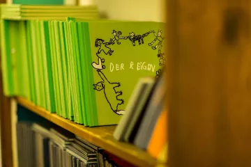 Mehrere Bücher stehen in einem Regal in der Werkstatt der Buchinder.