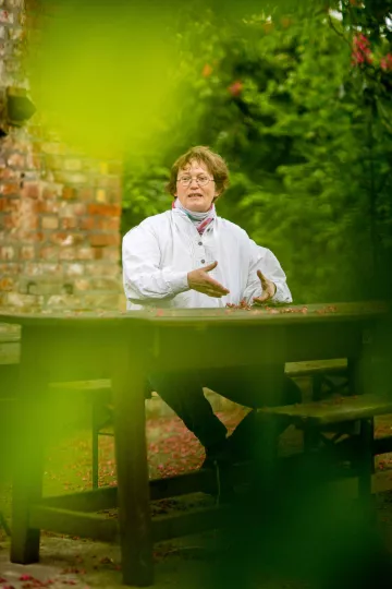 Christina Weiß sitzt an einem Tisch im Garten des Hauses in dem sie lebt.