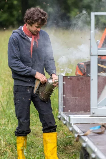 Christopher Mann räuchert die Bienenstöcke ein, um die Bienen zu beruhigen.