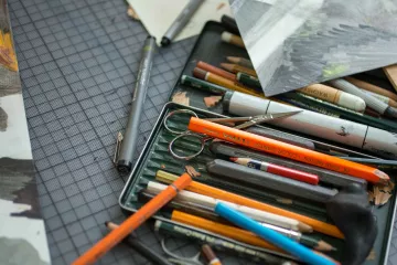 Stifte, Papier und eine Schere auf einem Schreibtisch.