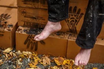 Verpackte Schachteln des Manifests im Hintergrund, während davor Helge Hommes Füße zu sehen sind.