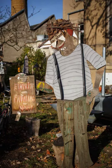 Eine Holzfigur begrüßt die Gäste am Hoftor.